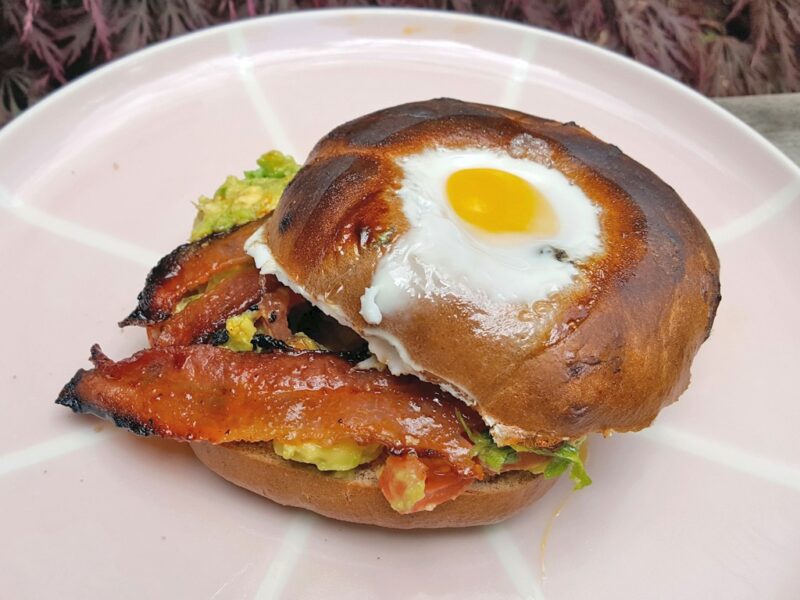 Egg in bagel with maple & chipotle glazed bacon and guacamole