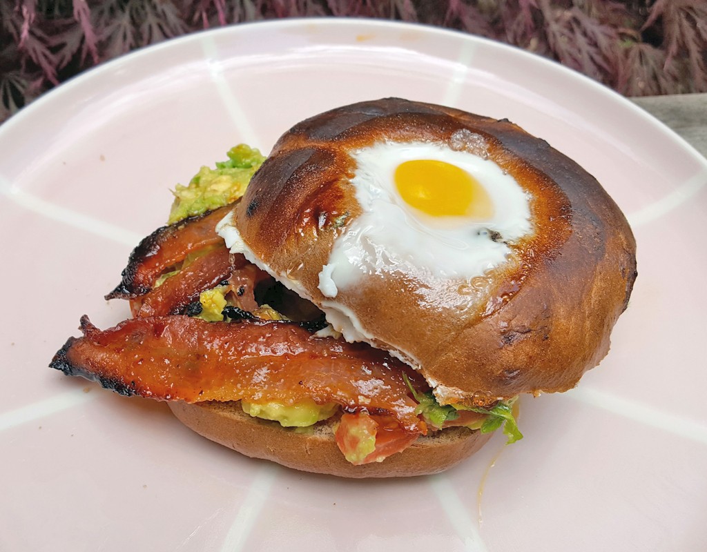 Egg in bagel with maple & chipotle glazed bacon and guacamole